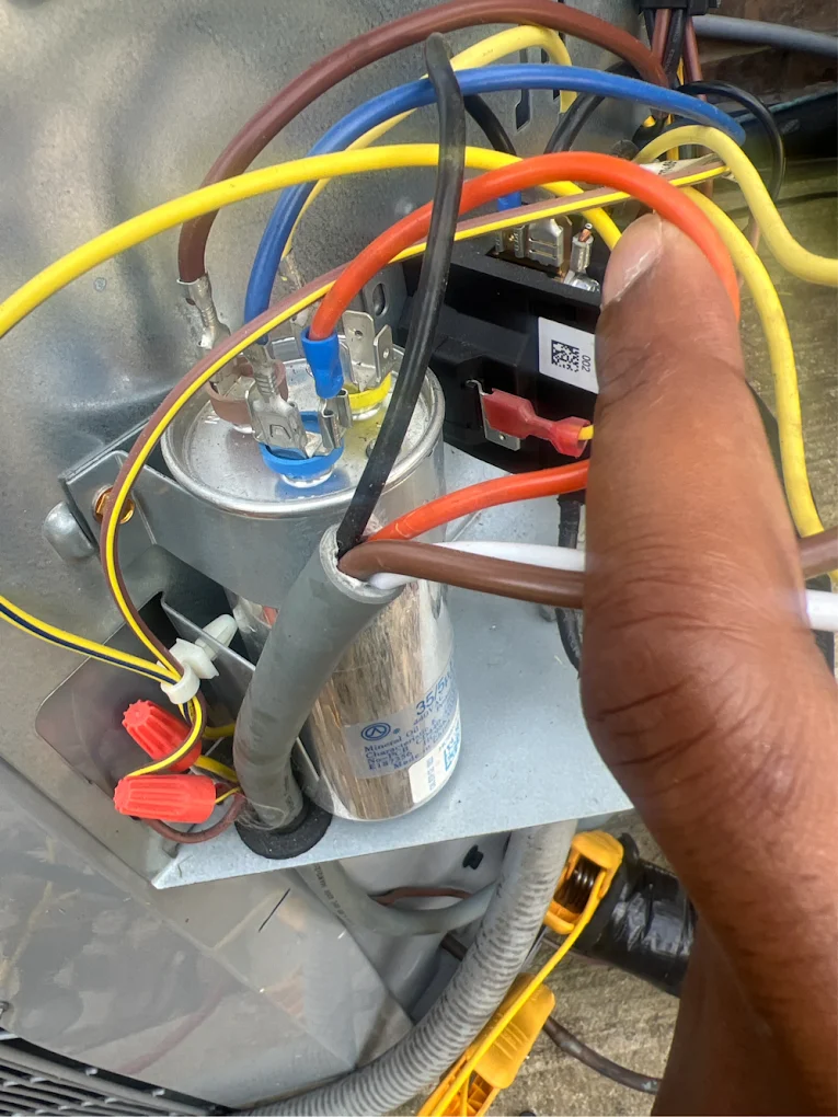 Technician testing an AC capacitor wiring