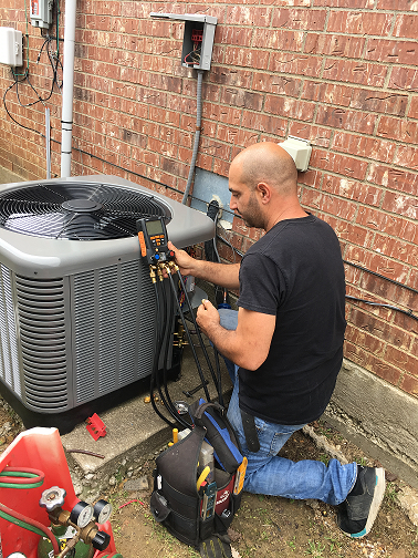 Technician checking refrigerant pressures on a condenser